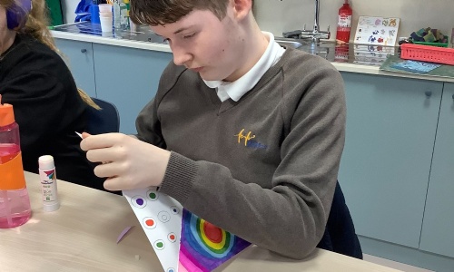 Member of Earth class about to fold their art work into a windmill.